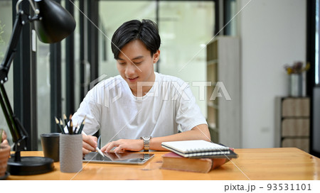Handsome Asian male university student concentrating doing his homework on tablet 93531101