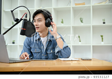 Talented Asian male radio host or VJ wearing headphones and speaking on his microphone 93531127