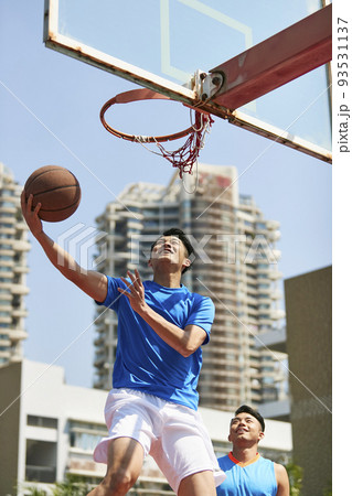 young asian adult players playing basketball on outdoor court young asian adult players playing basketball on outdoor court 93531137