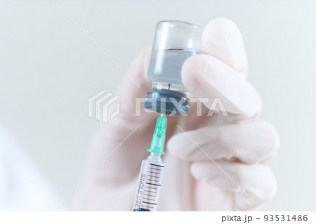 バイアル瓶から注射薬を吸う医師の手元 93531486