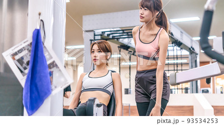 スポーツジムでウエイトトレーニングの説明を受ける若い女性 スポーツジムでウエイトトレーニングの説明を受ける若い女性 93534253