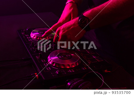 Dj mixing on turntables with color light effects. Soft focus on hand. Close-up. Dj mixing on turntables with color light effects. Soft focus on hand. Close-up. 93535700