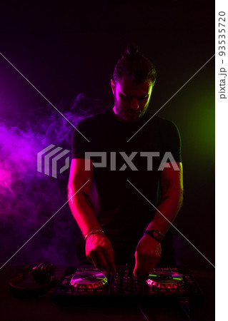 Attractive young DJ playing on turntables with color light effects 93535720