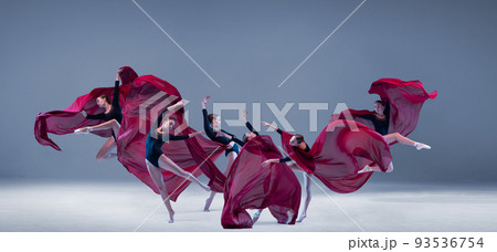 Portrait of young ballerina dancing with deep red clored fabric isolated over blue grey studio background. Flower bloom. Art style Portrait of young ballerina dancing with deep red clored fabric isolated over blue grey studio background. Flower bloom. Art style 93536754