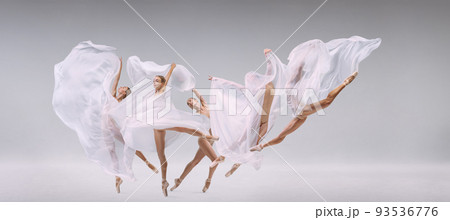 Portrait of young ballerina dancing with transparent white fabric isolated on grey studio background. Development of movements 93536776