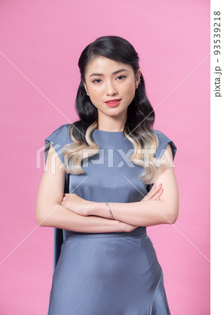 Asian young beautiful female model in trendy dress standing posing holding hand up crossed arm smiling look at camera on pink background. Asian young beautiful female model in trendy dress standing posing holding hand up crossed arm smiling look at camera on pink background. 93539218