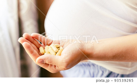 Prenatal vitamins pill. Happy smiling woman taking pill with supplement vitamin Omega 3. Vitamin D, E, A Fish Oil Capsules. 93539265