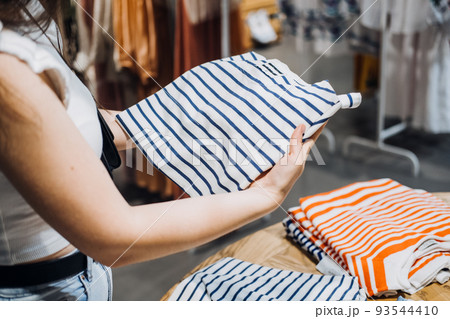 Modern Latina young woman choosing 100 percent organic cotton wear t shirt in modern eco-friendly shop 93544410