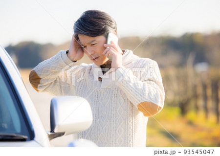 車が故障して電話をかけるミドル男性 93545047