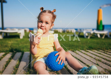 Adorable toddler girl eating ice cream outdoors 93545758