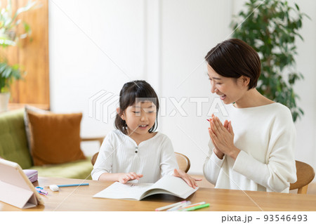リビングで勉強する小学生の女の子を手を叩いて褒めるママ 93546493