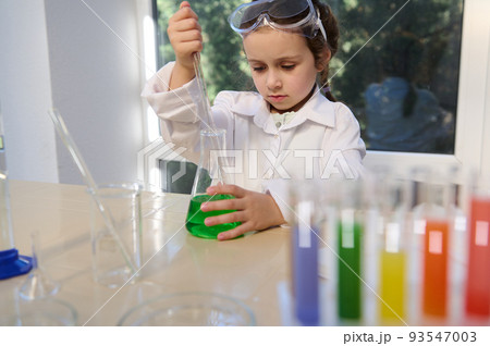 Little European preschooler girl making scientific experiments, fascinated and inspired by learning Chemistry. Science, chemical education concept. Back to school in the new academic year semester 93547003