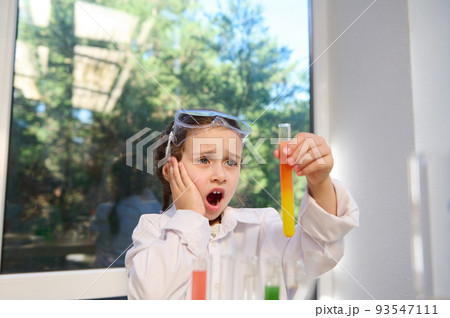 Smart Caucasian schoolgirl watching fascinating wonderful chemical reaction, between multi-colored chemicals and reagents, taking place in a test tube that she holds in her hands at a chemistry lesson Smart Caucasian schoolgirl watching fascinating wonderful chemical reaction, between multi-colored chemicals and reagents, taking place in a test tube that she holds in her hands at a chemistry lesson 93547111