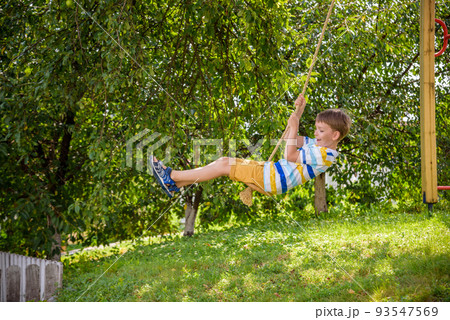 Two adorable happy little boys is having fun on a rope swing which he has found while having rest outside city. Active leisure time with children Two adorable happy little boys is having fun on a rope swing which he has found while having rest outside city. Active leisure time with children 93547569