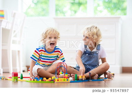Kids play wooden railway. Child with toy train. 93547897