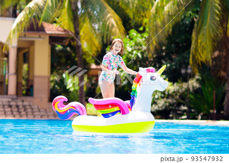 Child on unicorn float in swimming pool. Kids swim 93547932