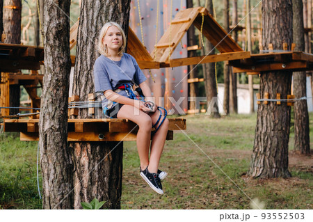 A girl passes an obstacle in a rope town. A girl in a forest rope park 93552503