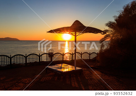 Sun umbrellas and chaise lounges on tropical beach at sunrise. Concept of rest, relaxation, holidays, resort 93552632