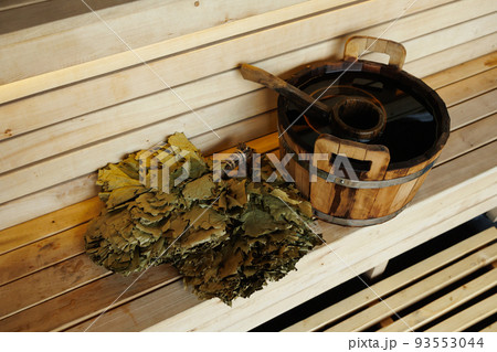 Sauna bucket full of water with ladle and broom on the wooden bench Sauna bucket full of water with ladle and broom on the wooden bench 93553044