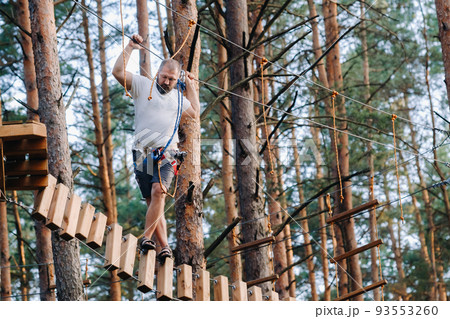 A man overcomes an obstacle in a rope town. A man in a forest rope park 93553260