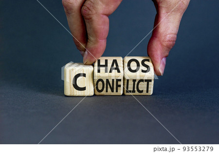 From conflict to chaos symbol. Concept words Conflict and Chaos on wooden cubes. Businessman hand. Beautiful grey background. Businessman hand. Business Conflict and Chaos concept. Copy space. 93553279