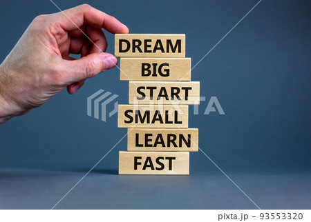 Dream big start small symbol. Words 'dream big start small learn fast' on wooden blocks on a beautiful grey background. Businessman hand. Business, motivational and dream big start small concept. Dream big start small symbol. Words 'dream big start small learn fast' on wooden blocks on a beautiful grey background. Businessman hand. Business, motivational and dream big start small concept. 93553320
