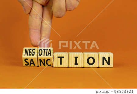 Sanction or negotiation symbol. Businessman turns cubes, changes the word sanction to negotiation. Beautiful orange table, orange background, copy space. Business, sanction or negotiation concept. 93553321