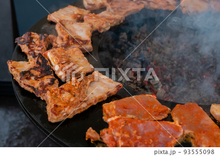 Process of cooking meat steaks on round brazier - close up Process of cooking meat steaks on round brazier - close up 93555098