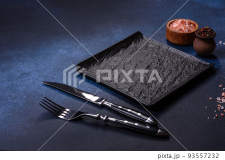 Empty square black plate on dark moody background with copy space Empty square black plate on dark moody background with copy space 93557232