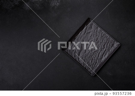Empty square black plate on dark moody background with copy space Empty square black plate on dark moody background with copy space 93557236