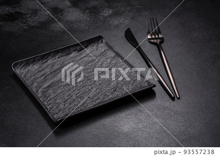 Empty square black plate on dark moody background with copy space Empty square black plate on dark moody background with copy space 93557238