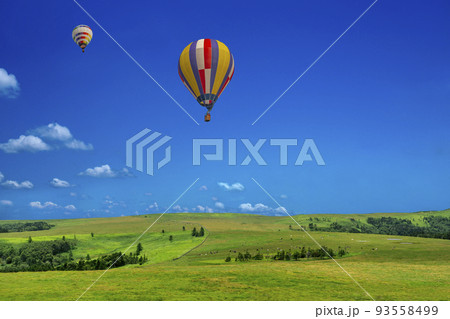 青空を背景にした地平線の見える草原と熱気球 93558499