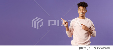 Portrait of enthusiastic, good-looking hispanic man with dreads, looking and pointing upper left corner with satisfied beaming smile, seeing cool thing, made his choice, purple background Portrait of enthusiastic, good-looking hispanic man with dreads, looking and pointing upper left corner with satisfied beaming smile, seeing cool thing, made his choice, purple background 93558986