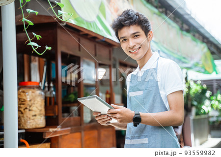 male chicken noodle seller wearing apron smiling using digital tablet 93559982