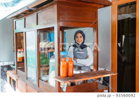Muslim woman seller wearing apron smiling with crossed hands 93560092