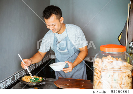 the seller cooks fried chicken noodles on a hot plate 93560362