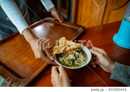 waiter's hand serving a bowl of chicken noodle dish waiter's hand serving a bowl of chicken noodle dish 93560443