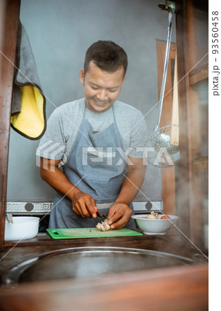 the seller slices the toppings while preparing the dish 93560458