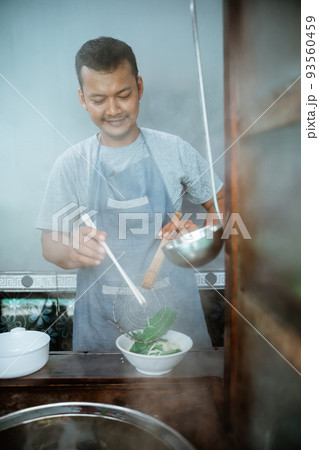 man seller pouring into the bowl of boiled noodles 93560459
