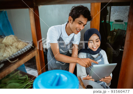 a couple of seller in aprons using tablet digital 93560477
