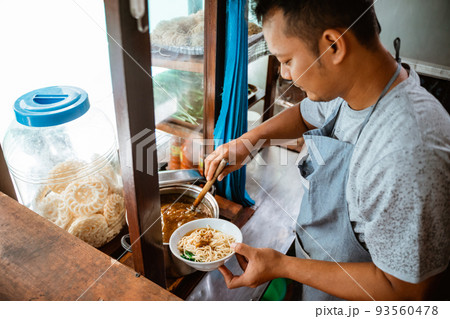 man seller giving chicken to noodles when preparing dishes 93560478
