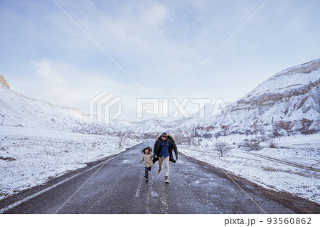 dad and daughter walking on empty street in winter dad and daughter walking on empty street in winter 93560862