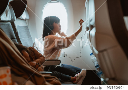 kid sitting on an airplane and watching movie 93560904