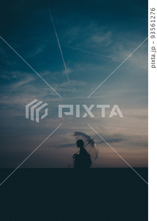 女性のシルエットと美しい夕焼け空 93561276