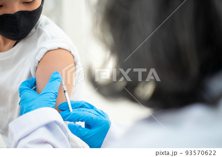 Doctor holding syringe for prepare vaccinated in the shoulder of Asian boy kids in the hospital. Pediatrician makes vaccination for kids. Vaccination, immunization, disease prevention concept. 93570622