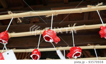 神社の境内に泳ぐ金魚の形をした赤い風鈴 神社の境内に泳ぐ金魚の形をした赤い風鈴 93570938