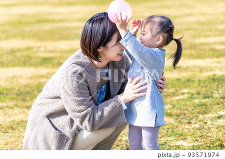 公園の芝生広場で遊ぶ園児と保育士 93571974