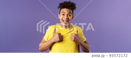 Close-up portrait of enthusiastic healthy hispanic guy staying positive, show thumbs-up and smiling, encourage people stay home, feel fine, like and approve friends plan, standing purple background 93572172