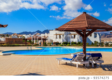 Chaise longues near a swimming pool. Concept of spa, rest, relaxation, holidays, resort Chaise longues near a swimming pool. Concept of spa, rest, relaxation, holidays, resort 93574275