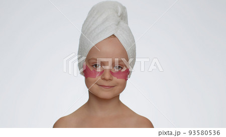 Smiling child girl applying pink patches under eyes, teenager natural skin care, perfect fresh clean Smiling child girl applying pink patches under eyes, teenager natural skin care, perfect fresh clean 93580536